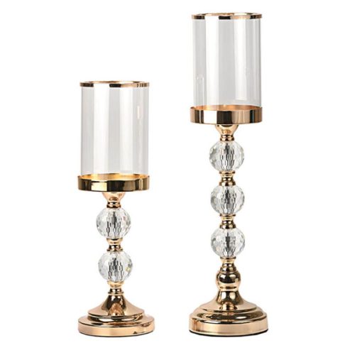 Ένα εντυπωσιακό σετ κηροπηγίων που εστιάζει στην έντονη λάμψη των κρυστάλλων. Σχεδιασμός: Χρυσή βάση και κορμός με πολυεδρικές (faceted) κρυστάλλινες μπάλες που θυμίζουν διαμάντια και διαθλούν το φως. Λεπτομέρεια: Το κυλινδρικό γυαλί διαθέτει χρυσό τελείωμα στο επάνω μέρος, προσδίδοντας ακόμα μεγαλύτερη πολυτέλεια.