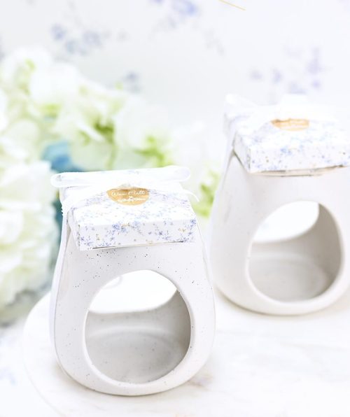 Κεραμικό blue toile μαζί με melt μέσα σε κουτάκι SoapTales Ένα κεραμικό melt burner που συνδυάζει φυσική ομορφιά και διακριτική πολυτέλεια. Με καθαρές γραμμές, φίνο λευκό κεραμικό και λεπτομέρειες με μπλε και χρυσά άνθη σε ρομαντικό vintage σχέδιο, μετατρέπει κάθε στιγμή σε εμπειρία χαλάρωσης και ζεστασιάς. Το προϊόν συνοδεύεται από αρωματικά wax melts τοποθετημένα επάνω στο καπάκι του κουτιού και δένεται με κομψή κορδέλα, έτοιμο να προσφερθεί ως δώρο ή μπομπονιέρα. Ιδανικό για όσους αγαπούν τη φυσική αισθητική και θέλουν να δημιουργήσουν μια ήρεμη, καλαίσθητη ατμόσφαιρα στον χώρο τους.