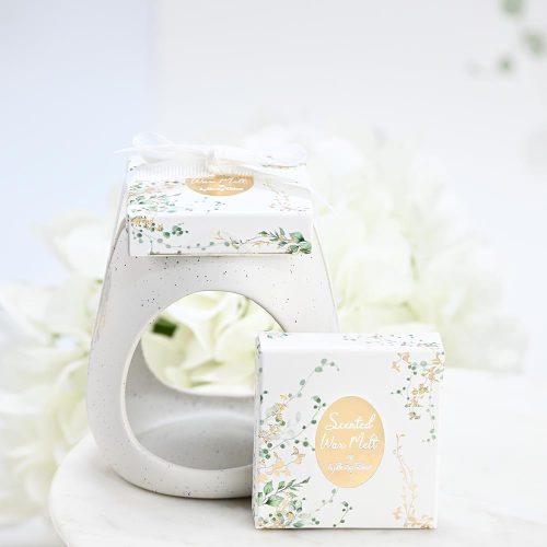 Κεραμικό eden μαζί με melt μέσα σε κουτάκι, SoapTales Ένα κεραμικό melt burner που συνδυάζει φυσική ομορφιά και διακριτική πολυτέλεια. Με καθαρές γραμμές, φίνο λευκό κεραμικό και λεπτομέρειες με χρυσό και απαλές πράσινες αποχρώσεις, μετατρέπει κάθε στιγμή σε εμπειρία χαλάρωσης και ζεστασιάς. Το προϊόν συνοδεύεται από αρωματικά wax melts τοποθετημένα επάνω στο καπάκι του κουτιού και δένεται με κομψή κορδέλα, έτοιμο να προσφερθεί ως δώρο ή μπομπονιέρα. Ιδανικό για όσους αγαπούν τη φυσική αισθητική και θέλουν να δημιουργήσουν μια ήρεμη, καλαίσθητη ατμόσφαιρα στον χώρο τους.