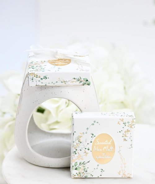 Κεραμικό eden μαζί με melt μέσα σε κουτάκι, SoapTales Ένα κεραμικό melt burner που συνδυάζει φυσική ομορφιά και διακριτική πολυτέλεια. Με καθαρές γραμμές, φίνο λευκό κεραμικό και λεπτομέρειες με χρυσό και απαλές πράσινες αποχρώσεις, μετατρέπει κάθε στιγμή σε εμπειρία χαλάρωσης και ζεστασιάς. Το προϊόν συνοδεύεται από αρωματικά wax melts τοποθετημένα επάνω στο καπάκι του κουτιού και δένεται με κομψή κορδέλα, έτοιμο να προσφερθεί ως δώρο ή μπομπονιέρα. Ιδανικό για όσους αγαπούν τη φυσική αισθητική και θέλουν να δημιουργήσουν μια ήρεμη, καλαίσθητη ατμόσφαιρα στον χώρο τους.